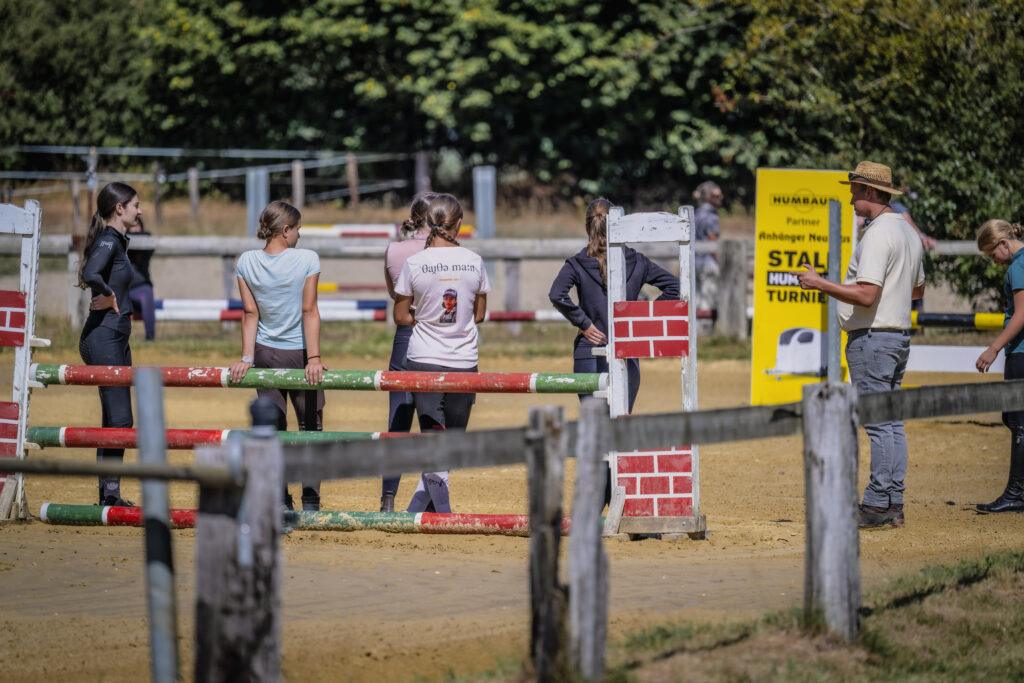 Reiterinnen und Trainer bei der gemeinsamen Besichtigung eines Hindernisparcours.